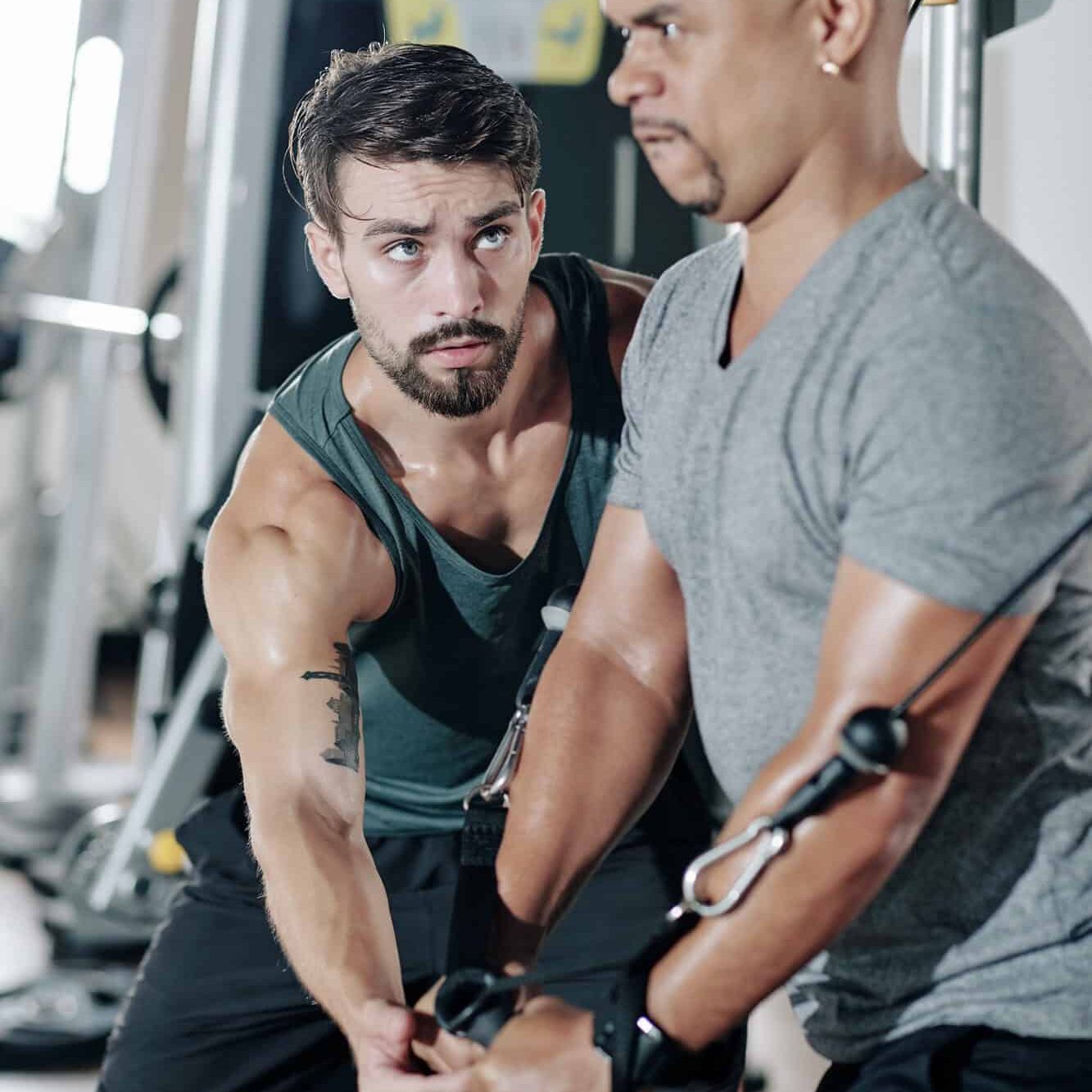 Treinador ajudando um cliente a fazer exercício de resistência em academia, promovendo fitness, treino personalizado e bem-estar.